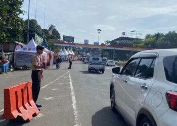 Anggota Pramuka membantu pejalan kaki menyeberang jalan di kawasan Pos Gadog Puncak Bogor