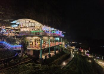 Pengunjung sedang menikmati kopi dengan latar belakang kabut dan pegunungan di Kopi Kabut Sevillage